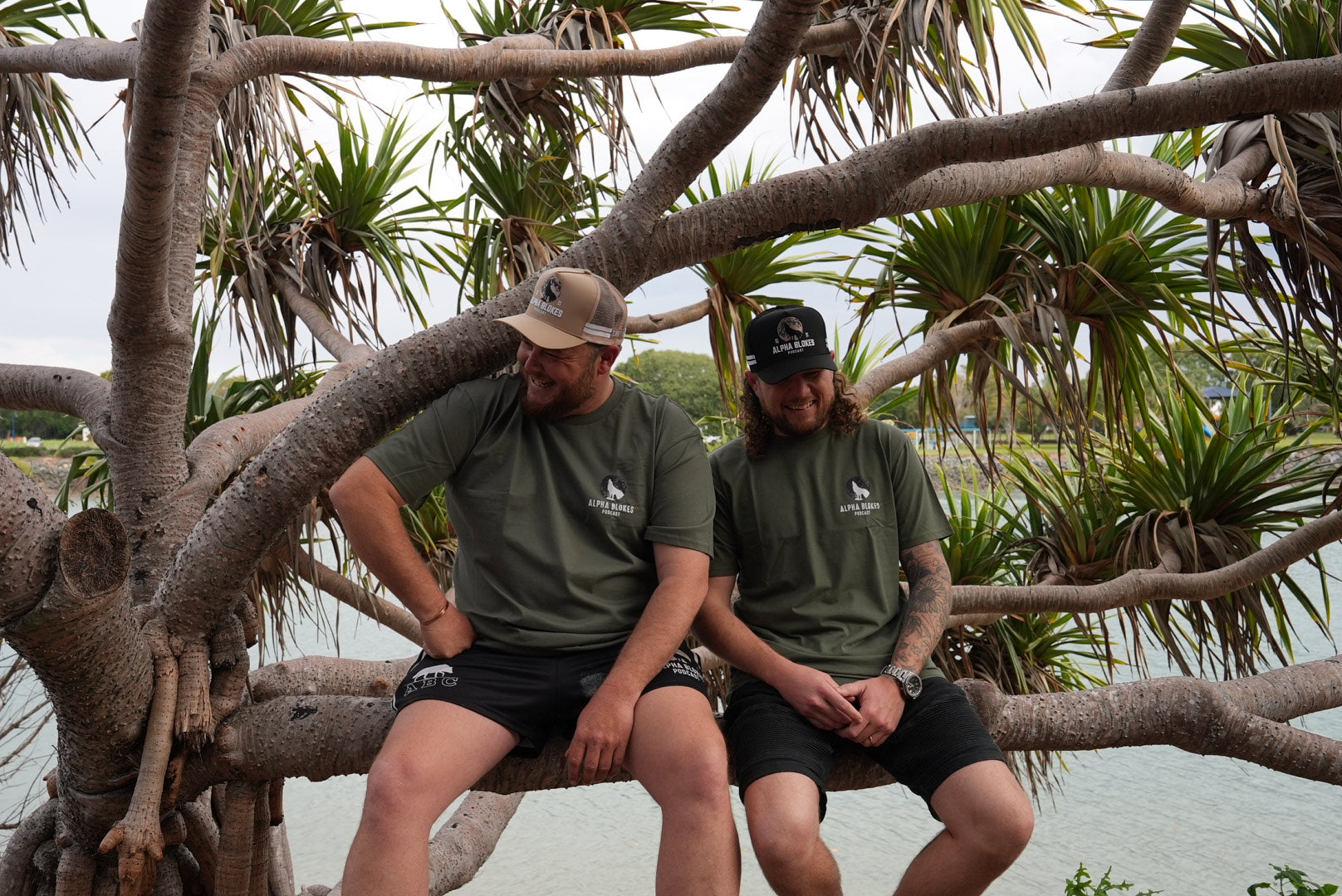 Two people sitting on a tree branch with a natural background