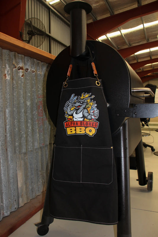 Black apron with a graphic design hanging on a smoker in a garage setting