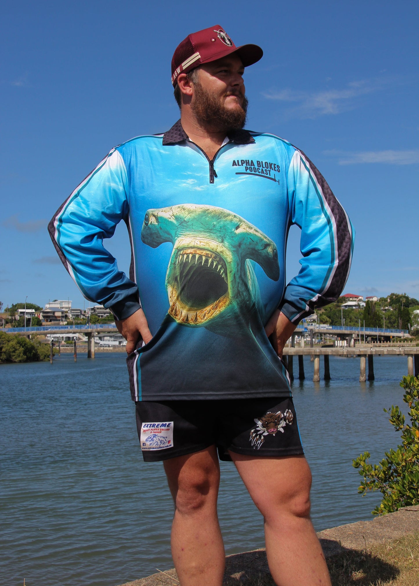 Man wearing a blue shirt with a shark design by a body of water