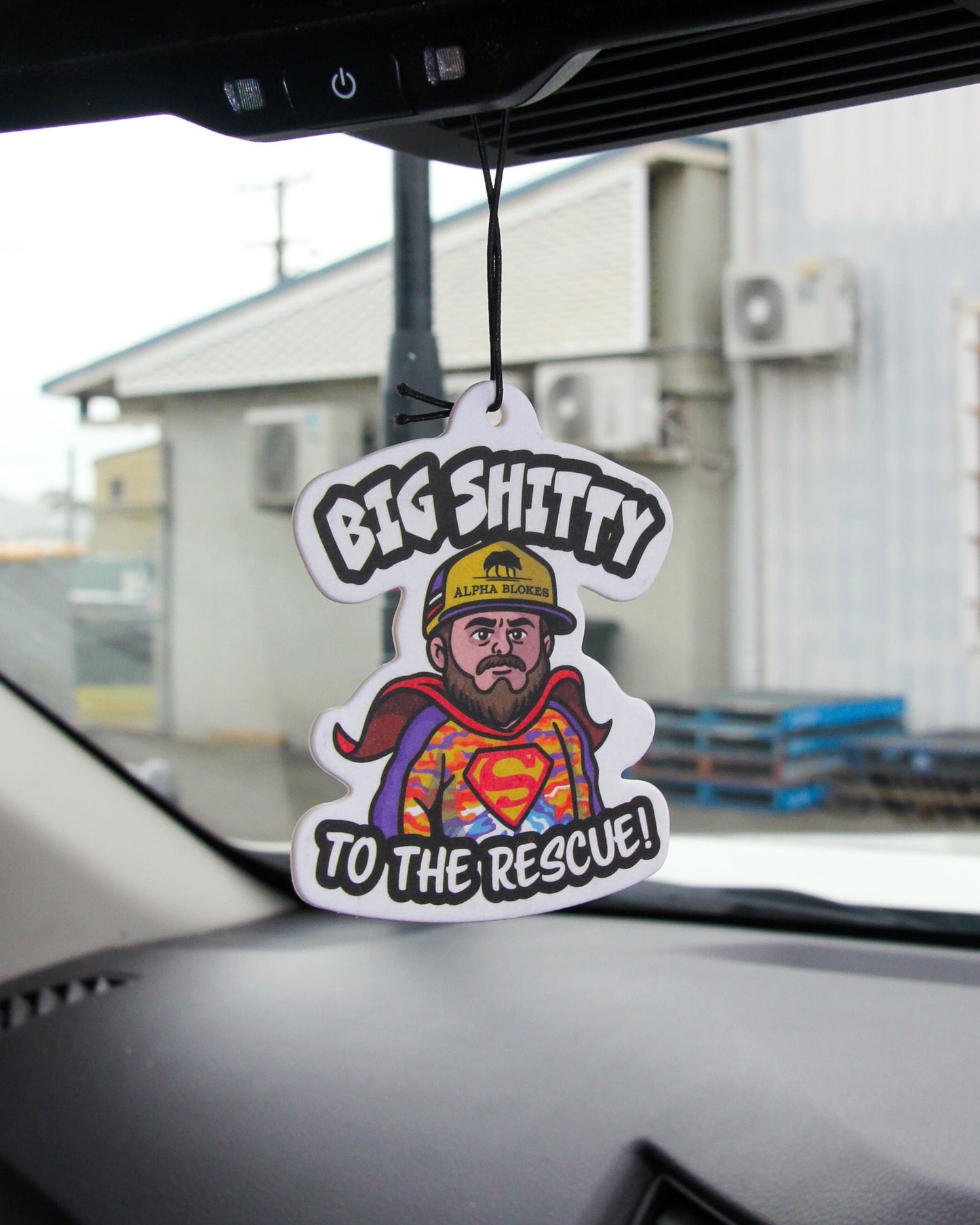 Car air freshener with a humorous design of a superhero in a hard hat hanging from a car's rearview mirror.