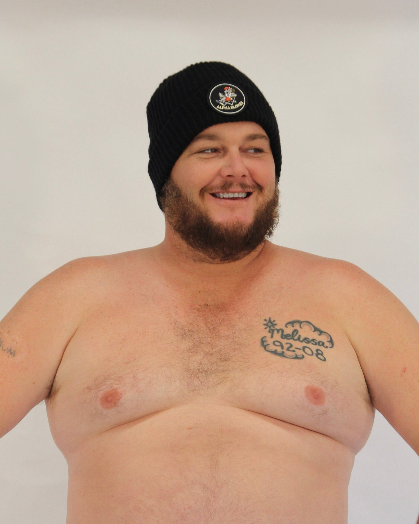 Man wearing a black beanie with a logo on a plain background