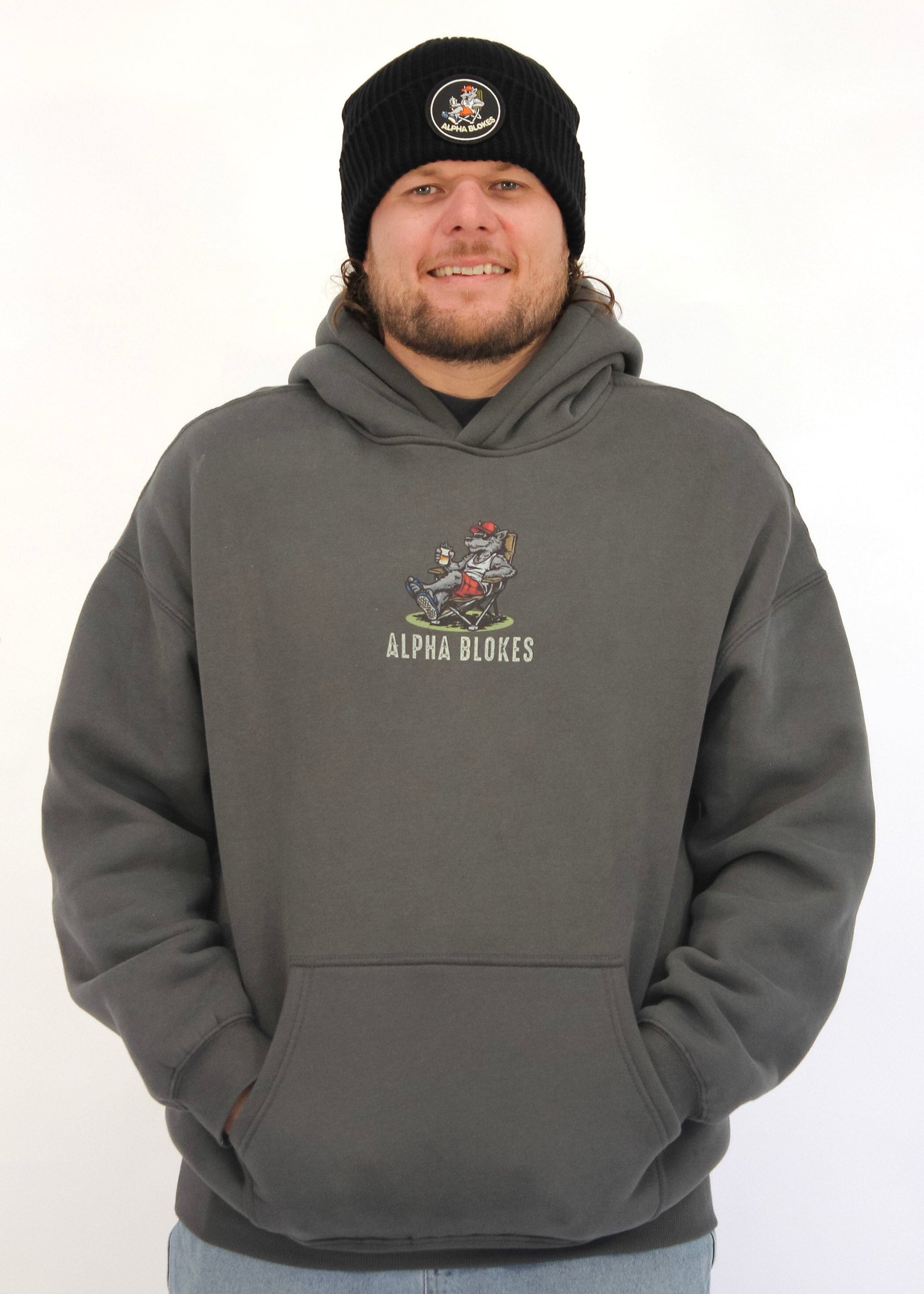 Man wearing a gray hoodie with a logo and text, standing against a white background